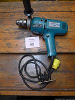 Full view of Makita HP1310 hammer drill with cord and chuck key on workbench