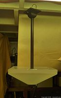 Full view of pendant showing frosted glass shade, metal stem, ceiling canopy