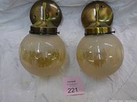 Front view of both antique brass wall sconces with amber glass globes