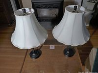 Pair of black metal table lamps with white fabric shades on a table