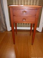 Front view of solid wood nightstand with two drawers and tapered legs