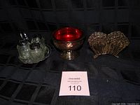 Group shot of all items: shakers on tray, red-lined compote, filigree holder