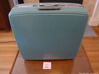 front view closed suitcase showing teal hard shell and handle