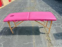 full view of unfolded pink massage table on pavement