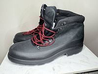 Side view of both black UGG boots showing red laces, rubber shell, debossed logo