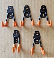 Front view of five of the six steel hooks showing mounting plates and orange-tipped prongs