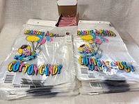 Two stacks of clear cotton candy bags with clown design and included box of red stripe ties visible
