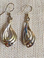 Front view of both sterling silver layered teardrop dangle earrings on fabric background
