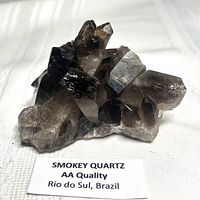 Smoky quartz cluster front view with label indicating AA quality and origin