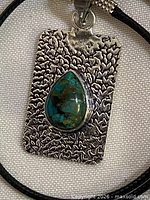 Front view of pendant showing chrysocolla cabochon and textured silver-plated rectangle