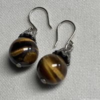 Full view of both tiger eye bead earrings with sterling hooks displayed on fabric