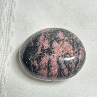 Front view of polished rhodonite stone showing pink and black veining