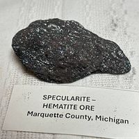Top view of reflective hematite specimen with identification label