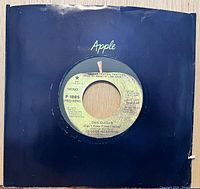 Front view of 7-inch record in black Apple sleeve showing label details