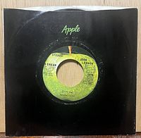Front of 45 in black Apple sleeve showing A-side label through centre cut-out