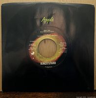 Record in black Apple company sleeve, front view