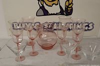 Group shot: pink pitcher, eight pink goblets, three clear martini glasses