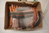 Open box containing multiple clear face shields with orange straps and foam padding