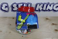 Jar with red lid containing many small phone fans, retail wrap label visible