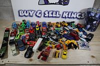Full lot overview with assorted vehicles, figures, fingerboard, fidget spinner