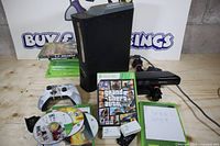 Full lot view: console standing, Kinect, controller, battery packs, power cords, GTA V case, loose discs and Overwatch cases