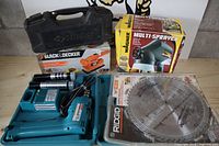 Overview of lot showing Husky case, Black & Decker sander box, Wagner sprayer box, Makita drill case and Ridgid-packaged blade