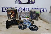 Group shot of controller, cased games, loose discs, storage case