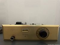 Front view showing faceplate, dial, knob, indicator window and branding
