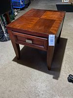 Overall view of wooden end table showing checkerboard veneer top and drawer front