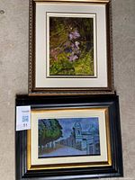 Two framed paintings: floral woodland scene above, architectural streetscape below
