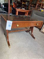 Three-quarter view of table showing glass top, drawer and leg design