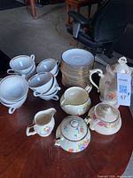 Overall view: stacked teacups, saucers, and five floral serving pieces displayed on table