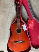 Full view of Yamaha G-120 guitar inside red-lined hard case with spare strings visible
