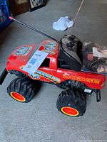 Left front view of red Dodge monster truck with controller and charger on hood