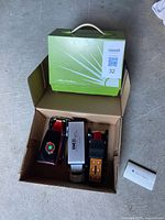 Lot overview in box showing toy sewing machine packaging and three vehicles