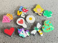 Group shot showing all 10 colourful Crocs shoe charms on grey surface