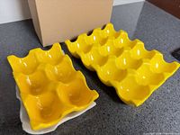 Two yellow ceramic egg trays beside box
