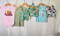 Overview of all five clothing items hung on hangers