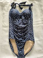 Front view of navy polka dot one-piece swimsuit showing halter ties, ruched front, beige lining