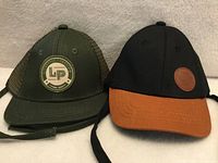 Front view of both L&P infant hats showing colors, logos and chin ties