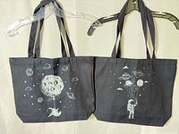 Both black tote bags side by side showing full designs and handles