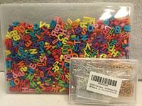 Closed boxes showing multicolour plastic letters and packaged metal letter charms