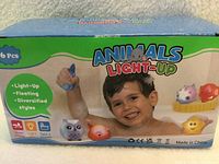 Front of sealed box showing product name, child in bath, six animal toys illustrated