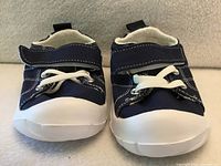 Front view of both shoes showing navy uppers, white stitching, elastic laces, hook-and-loop straps, and white rubber soles