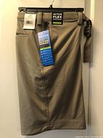 Front view of khaki Haggar Active Series shorts showing tags and built-in adjustable belt