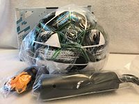 Soccer ball in plastic bag with pump and mesh net in front of original box