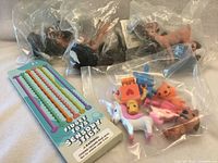 Packaged fidget sensory stick set, three bagged horse figures and bag of small figurines