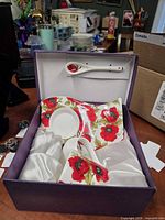 Open gift box showing creamer, saucer, spoon and satin lining