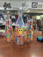 bottle flanked by two stacks of owl-print tumblers