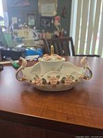 Front view of covered candy dish showing full form, handles and floral appliqué